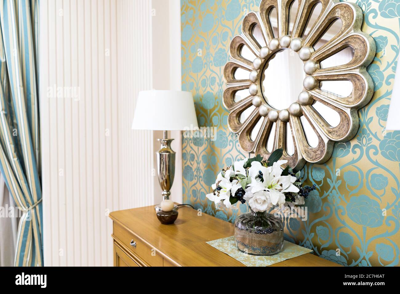 Stilvolle Vintage-Stil Home Interieur mit Holzkommode und dekoriert runden Spiegel. Symmetrische Leselampen auf Kommode. Selektive Fokussierung auf schöne Stockfoto