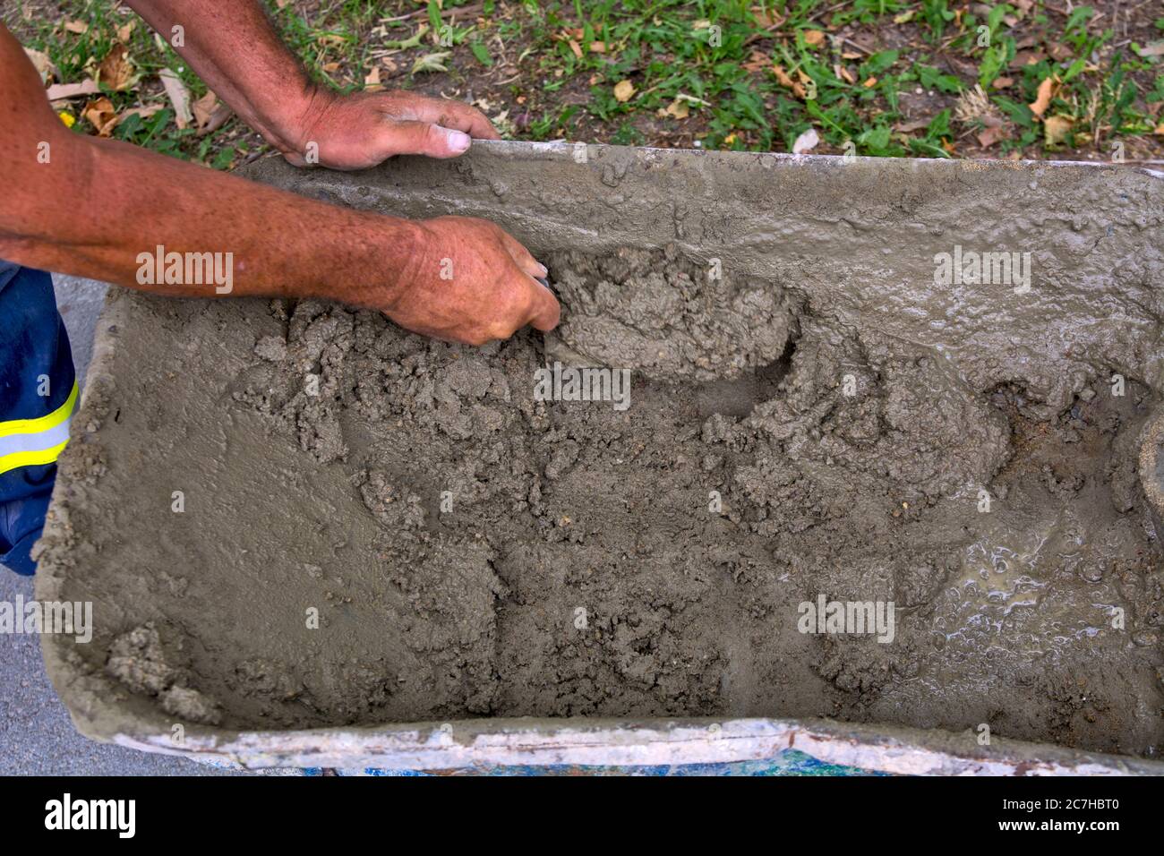 Meister, der an der Verputzung arbeitet, nimmt vorbereiteten Mörtel von Handkarren. Stockfoto