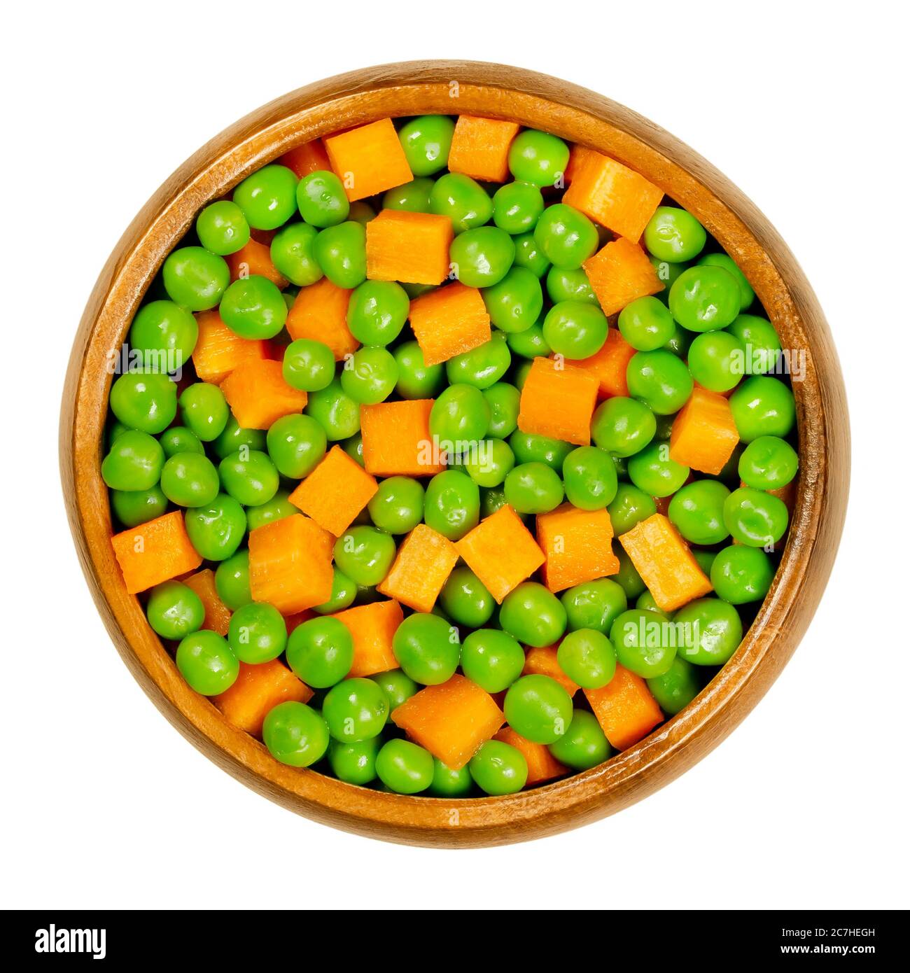 Grüne Erbsen und Karottenwürfel in Holzschüssel. Gemischtes Gemüse. Samen von Hülse Frucht Pisum sativum und orange gefärbte Würfel von Karotten, Daucus carota. Stockfoto