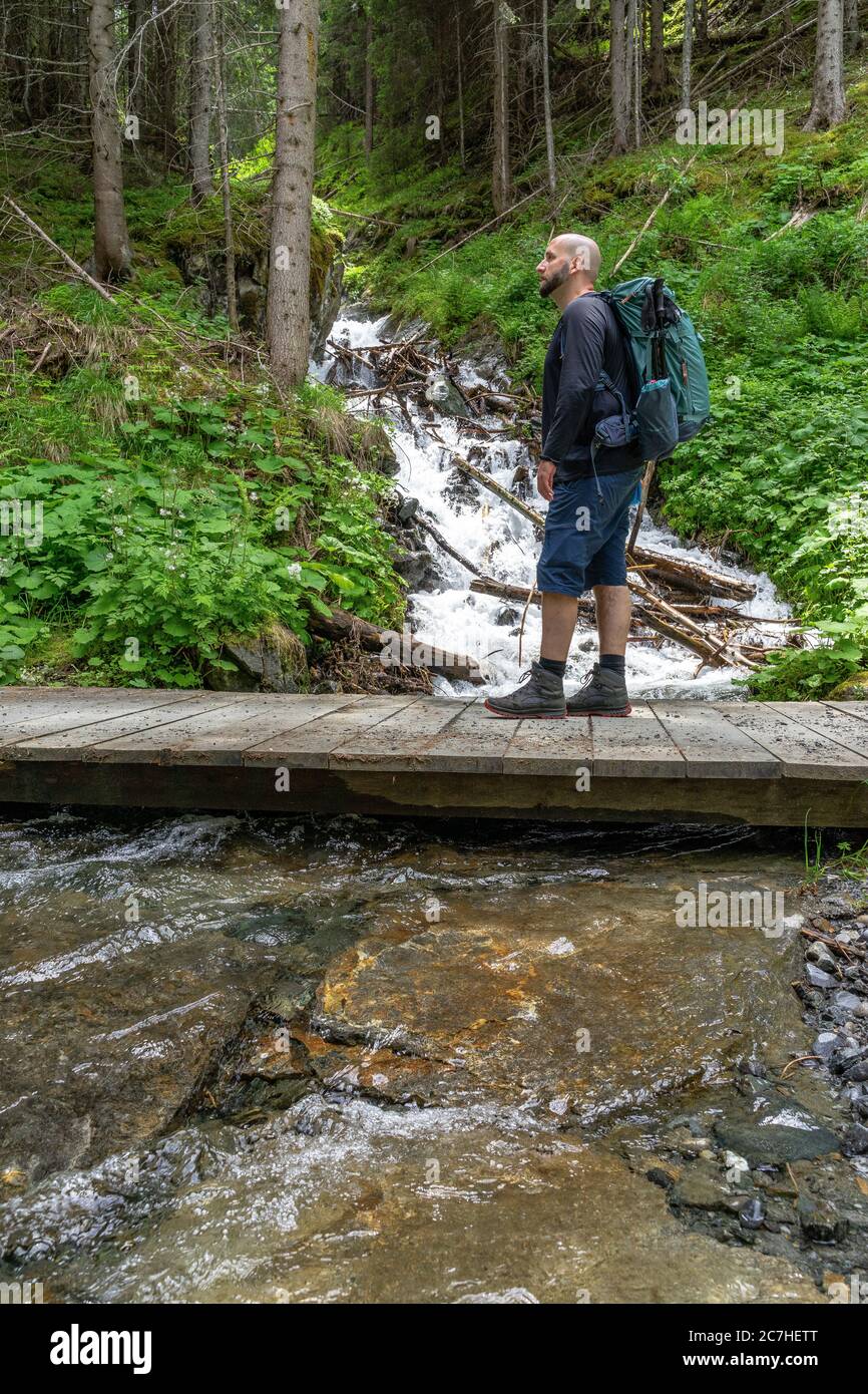 Europa, Österreich, Tirol, Ötztal Alpen, Ötztal, Wanderer auf einer kleinen Holzbrücke im Bergwald oberhalb von Sölden Stockfoto