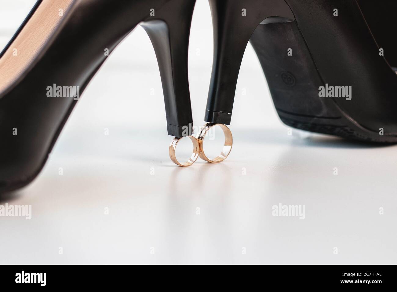Eheringe der Braut und des Bräutigams und schwarze Schuhe auf weißem Hintergrund. Hochzeitstag. Stockfoto