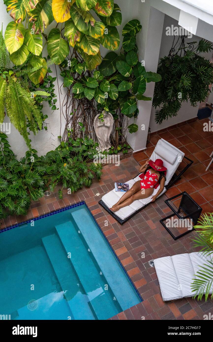 Amerika, Karibik, Großantillen, Dominikanische Republik, Santo Domingo, Zona Colonial, Hotel Colonial 154 H Boutique, Frau mit Sonnenhut auf einer Liege am Pool Stockfoto