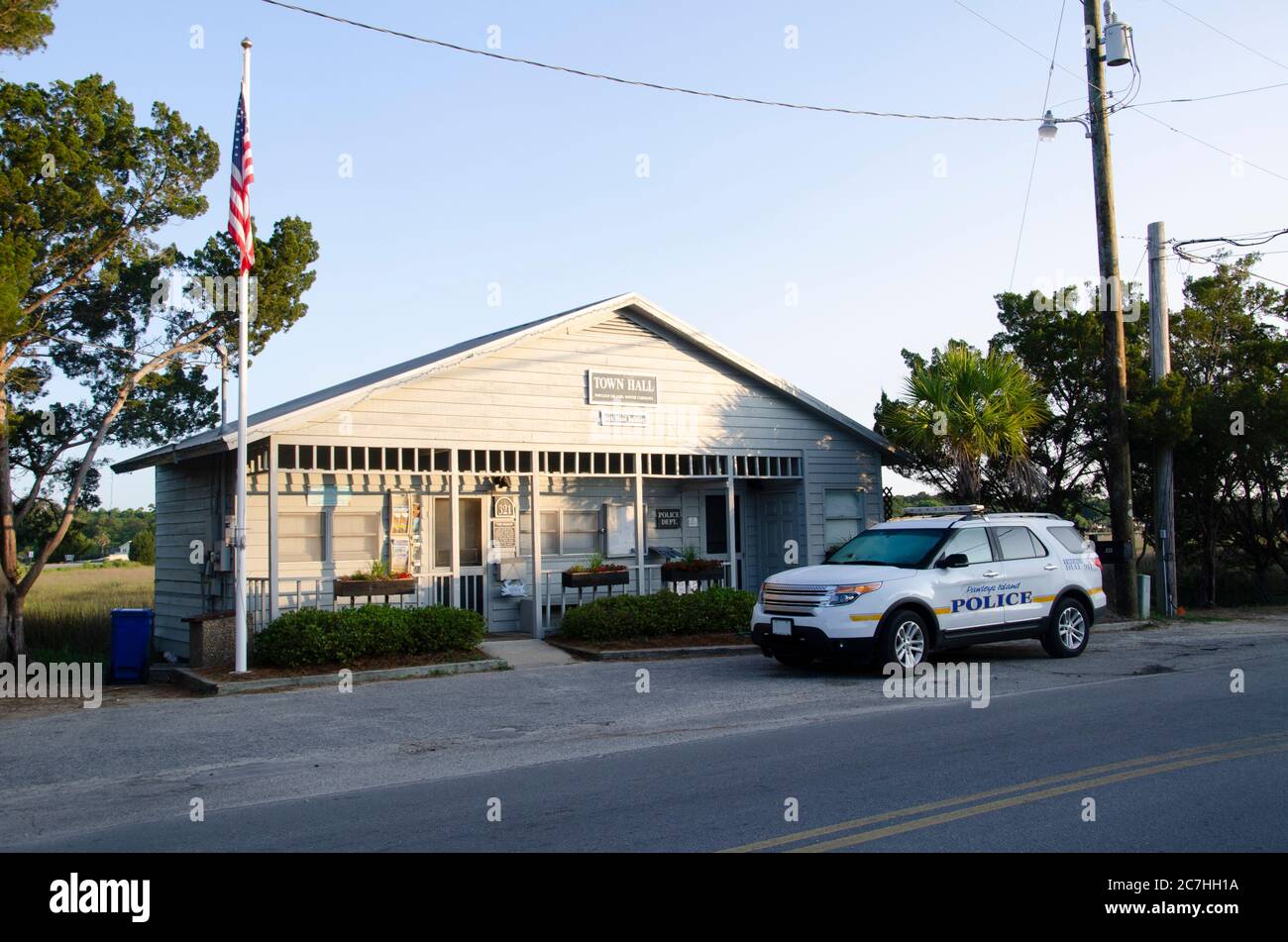 Ein kleines Holzgebäude in der frühen Morgensonne, das als Rathaus und Polizeibehörde fungiert, mit einem Polizeifahrzeug, das draußen geparkt ist. Eine Fahne hängt o Stockfoto