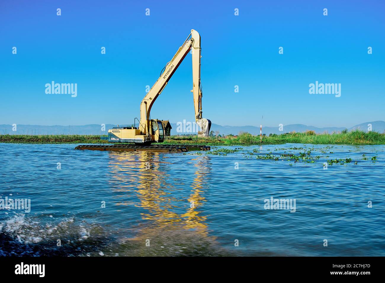 Bagger baggert und reinigt den See auf einer schwimmenden Stelle Stockfoto