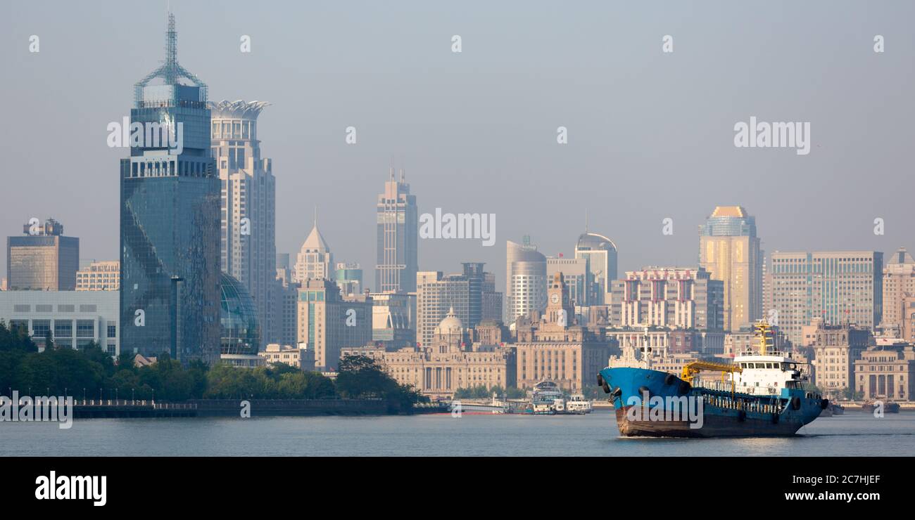 Containerschiff auf dem Huangpu River. Shanghai Puxi mit dem Bund (Waitan) im Hintergrund. Stockfoto