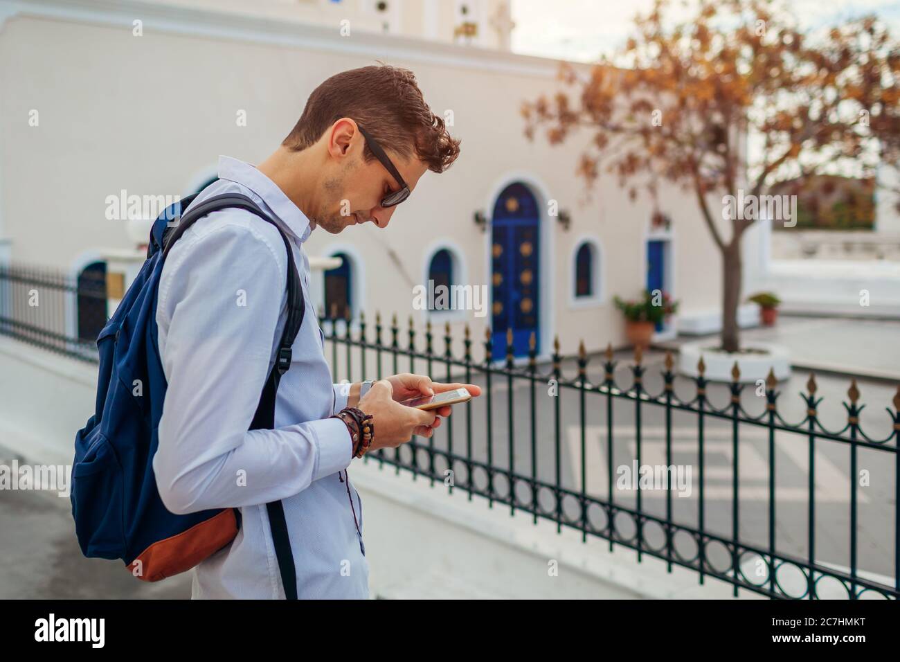 Santorini Reisende mit Smartphone auf der Straße. Mann mit Rucksack, der Navigator überprüft. Tourismus, Reisen, Urlaub Stockfoto Santorini Reisende mit Smartphone auf der Straße. Mann mit Rucksack, der Navigator überprüft. Tourismus, Reisen, Urlaub Stockfoto
