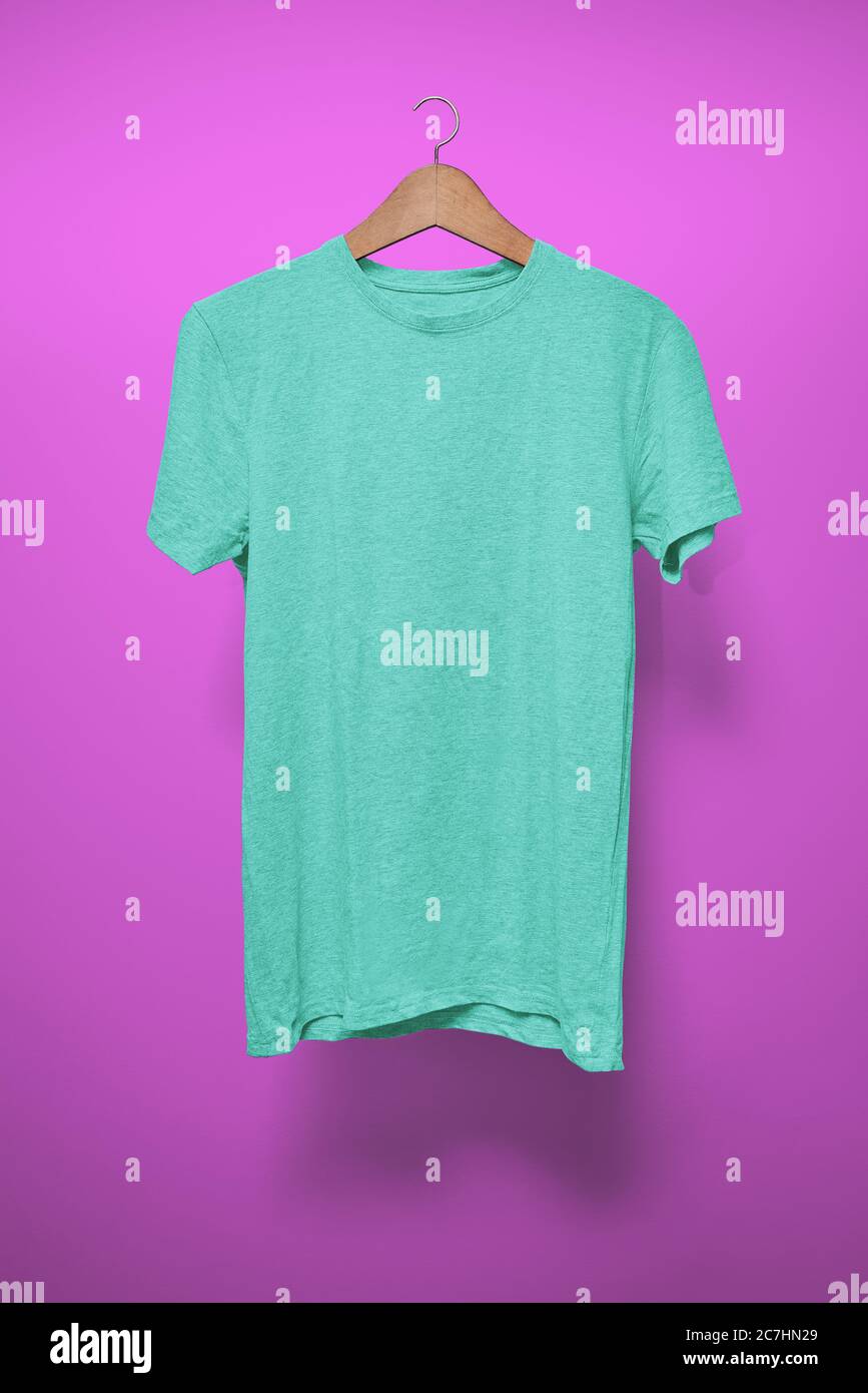 Türkisfarbenes T-Shirt auf einem Kleiderbügel vor einem lila Hintergrund Stockfoto