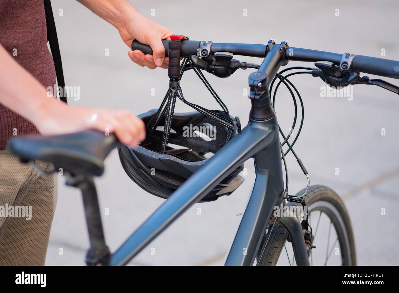 Pendlerfahrrad in den Händen eines männlichen Millennial, städtischen Hintergrund. Sicheres Radfahren in der Stadt, aktiver urbaner Lebensstil, Messenger oder Delivery man Konzept Stockfoto