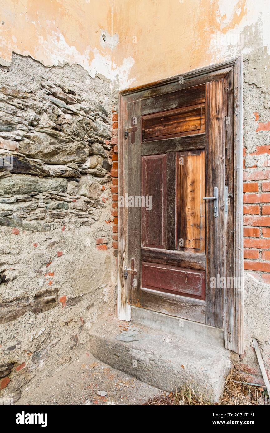 Eine alte Holztür in einer zerbröckelten Wand (verlorene Plätze) Stockfoto