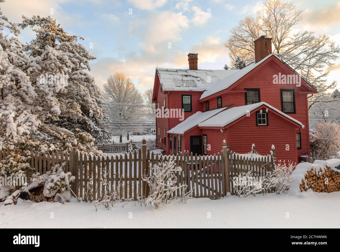 Titel Dunkel rosa gemalt 18. Jahrhundert New England Klapptafel zu Hause am verschneiten Tag in der Dämmerung. Die Szene umfasst einen Zaun, schneebedeckten Holzstapel, Schneedecke Stockfoto