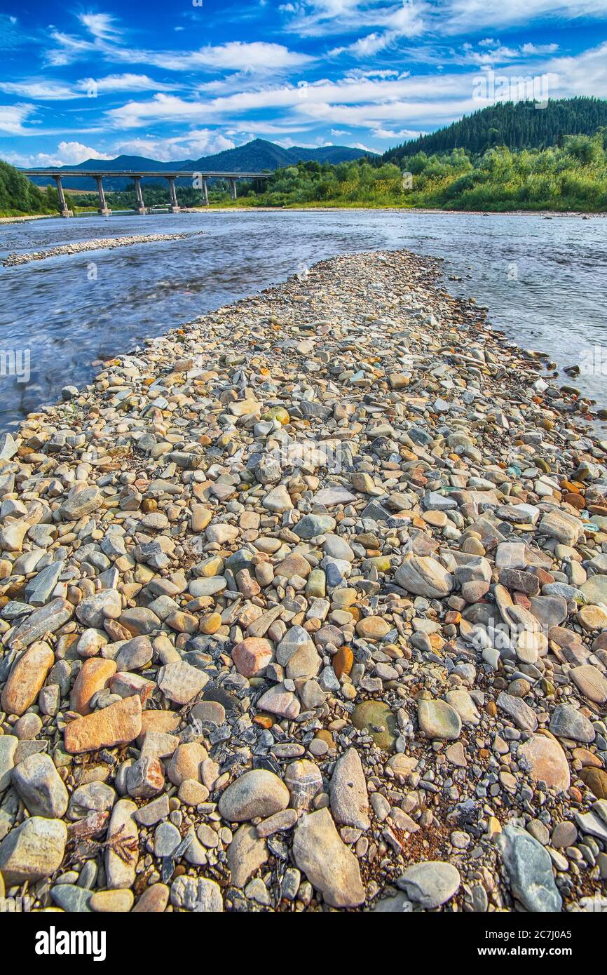 Gebirgsfluss von Wasser in den Felsen mit majestätischem blauen Himmel. Klarer Fluss mit Felsen. Steinvordergrund. Karpaten. Ukraine Stockfoto