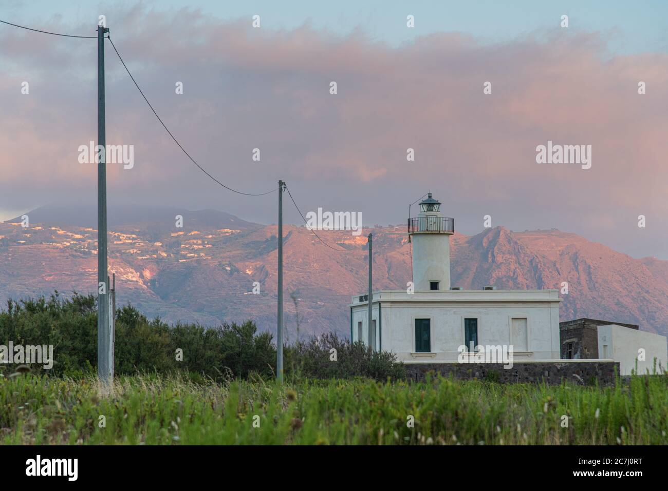 Sizilien - sonnige Eindrücke der Äolischen Inseln, auch als Äolische Inseln oder Isole Eolie bekannt: Lipari, Stromboli, Salina, Vulcano, Panarea, Filicudi und Alicudi. Leuchtturm auf der Insel Salina in Lingua bei Sonnenuntergang. Im Hintergrund die Insel Lipari. Stockfoto