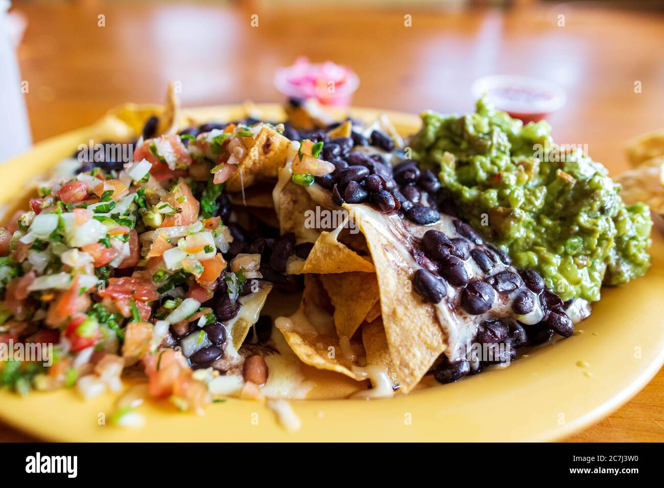 Nahaufnahme Nachos mit schwarzen Bohnen, geschmolzenem Käse, Tomatensalsa und Guacamole Stockfoto