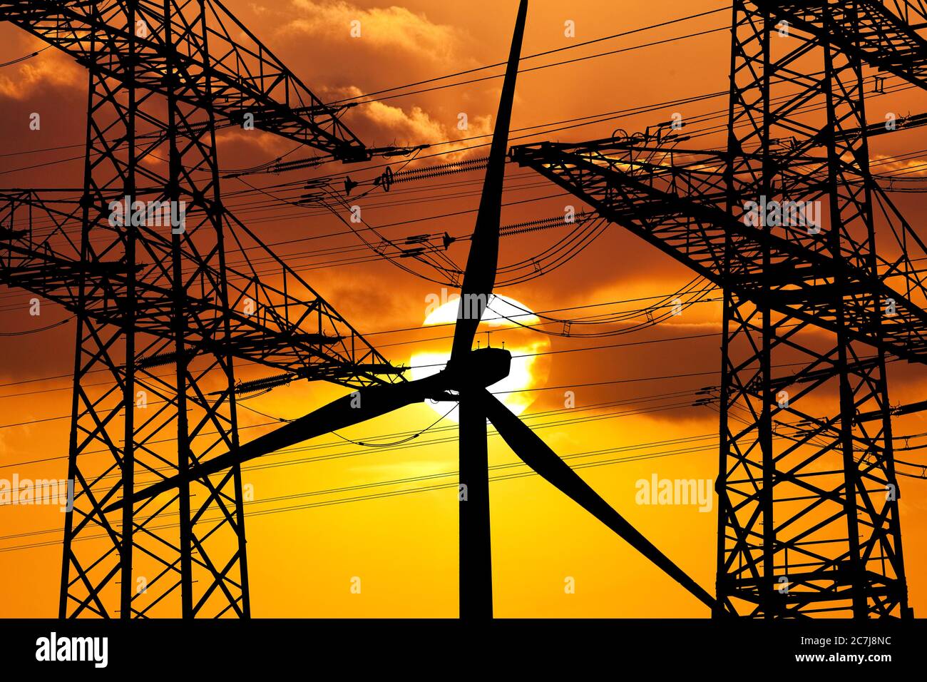 Zwei Strommasten und ein Windrad vor Sonne, Deutschland, Nordrhein-Westfalen, Ruhrgebiet, Witten Stockfoto