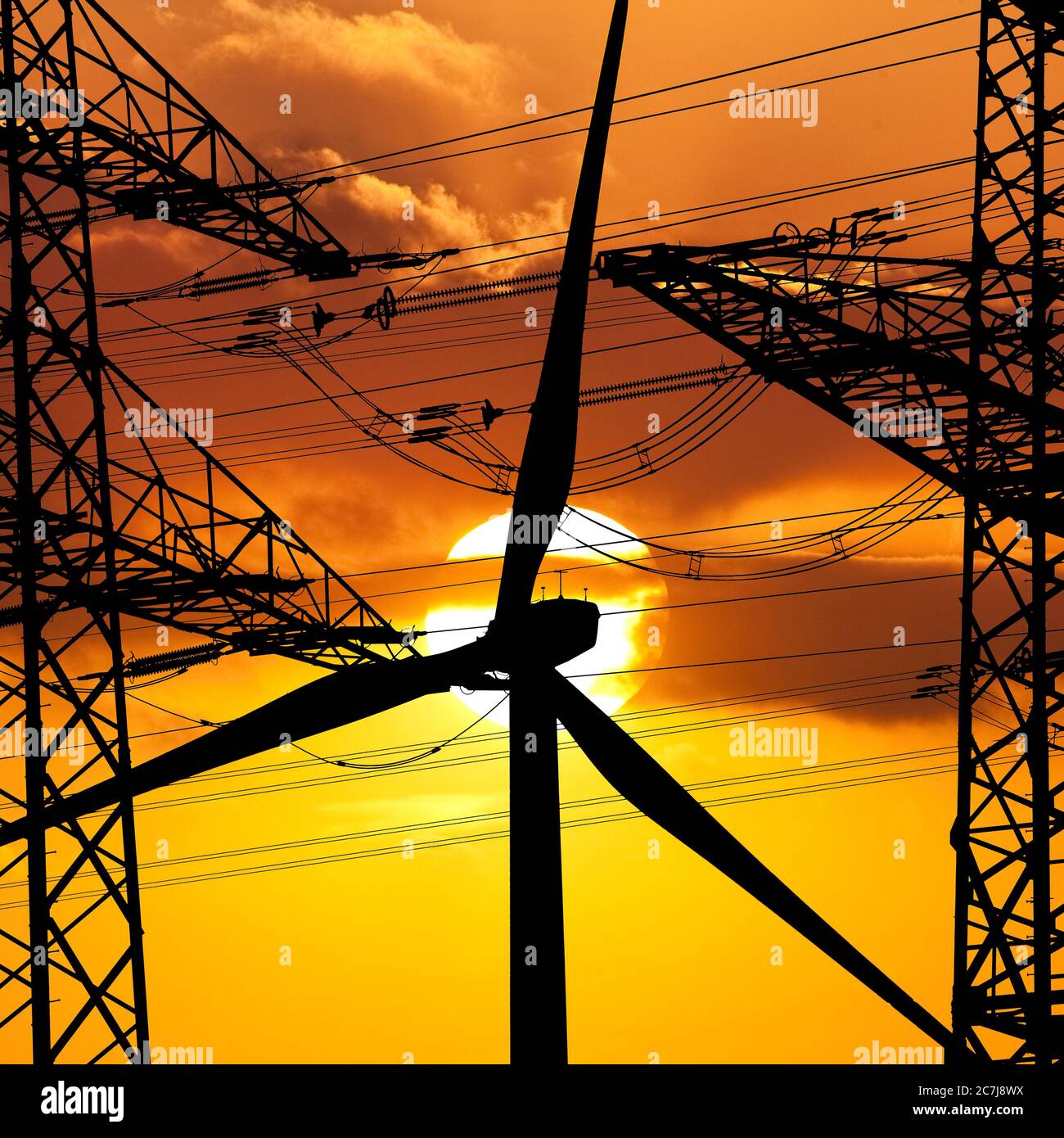 Zwei Strommasten und ein Windrad vor Sonne, Deutschland, Nordrhein-Westfalen, Ruhrgebiet, Witten Stockfoto