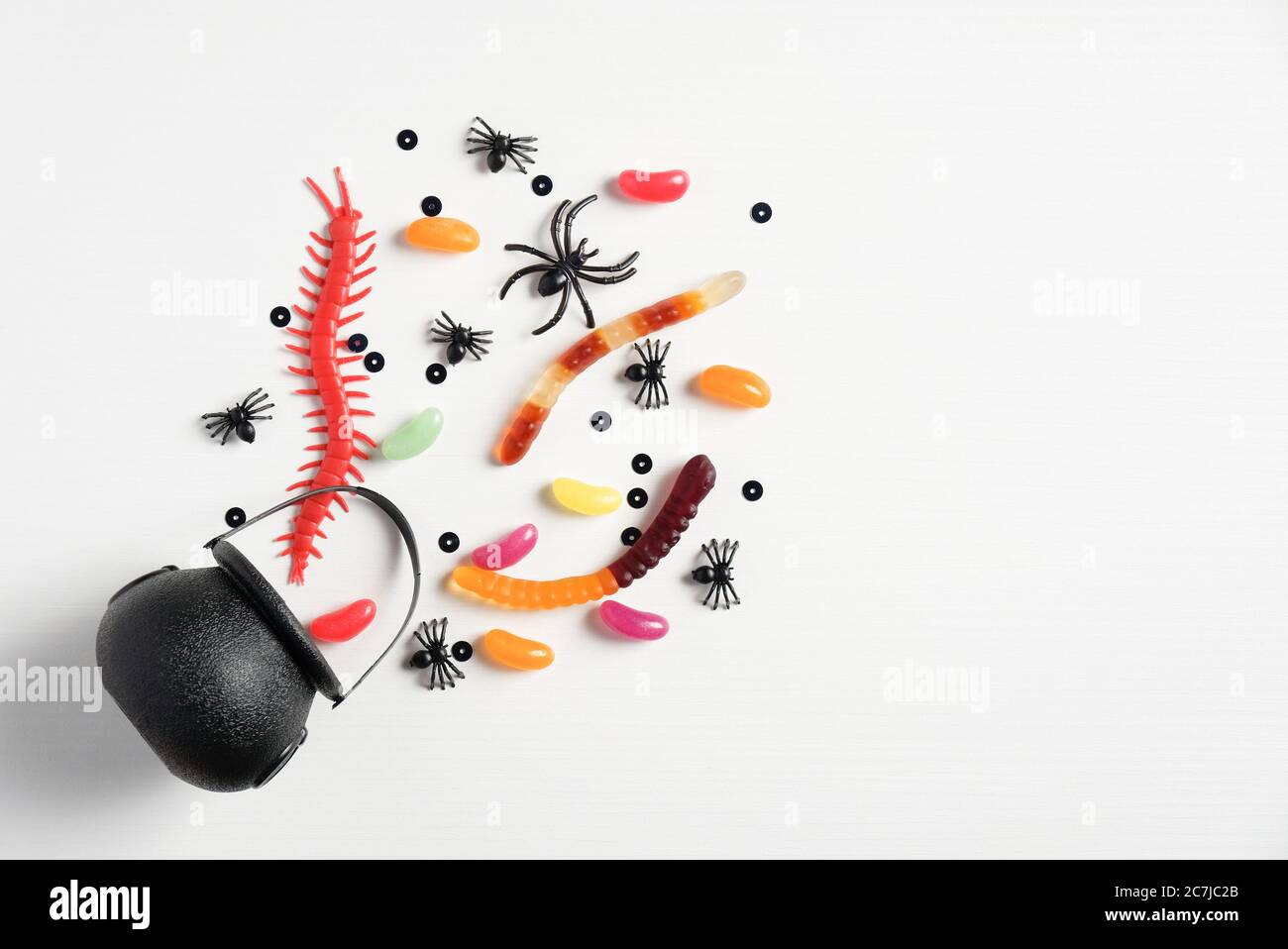 Halloween-Konzept. Kreative flache Lay-Komposition mit Topf und halloween Bonbons auf weißem Hintergrund. Stockfoto
