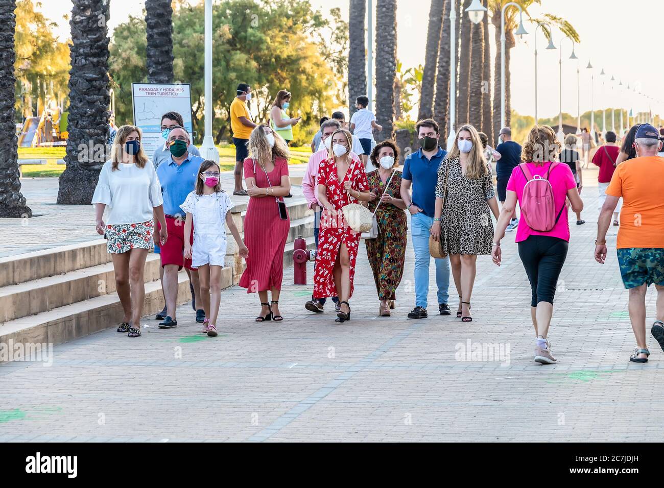 Huelva, Spanien - 3. Juni 2020: Menschen, die bei Sonnenuntergang an der Islantilla Promenade entlang gehen, tragen eine Schutzmaske wegen Covid-19. Stockfoto
