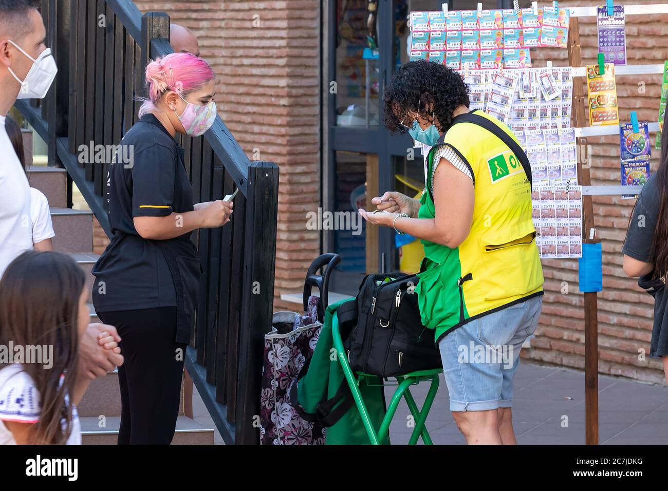 Huelva, Spanien - 4. Juli 2020: Blinde Frau in Gesichtsmaske Verkauf von Lotterielos für Blinde zu helfen. 'Once' Organisation am Strand von Islantilla Stockfoto
