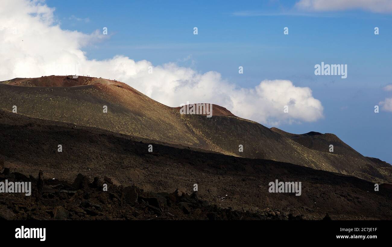 Ätna, Nationalpark Ätna, Parco dell –´Ätna, Kette von Ätna Sekundärgipfeln, brauner Lavahang im Vordergrund, blauer Himmel, dicke weiße Wolken Stockfoto