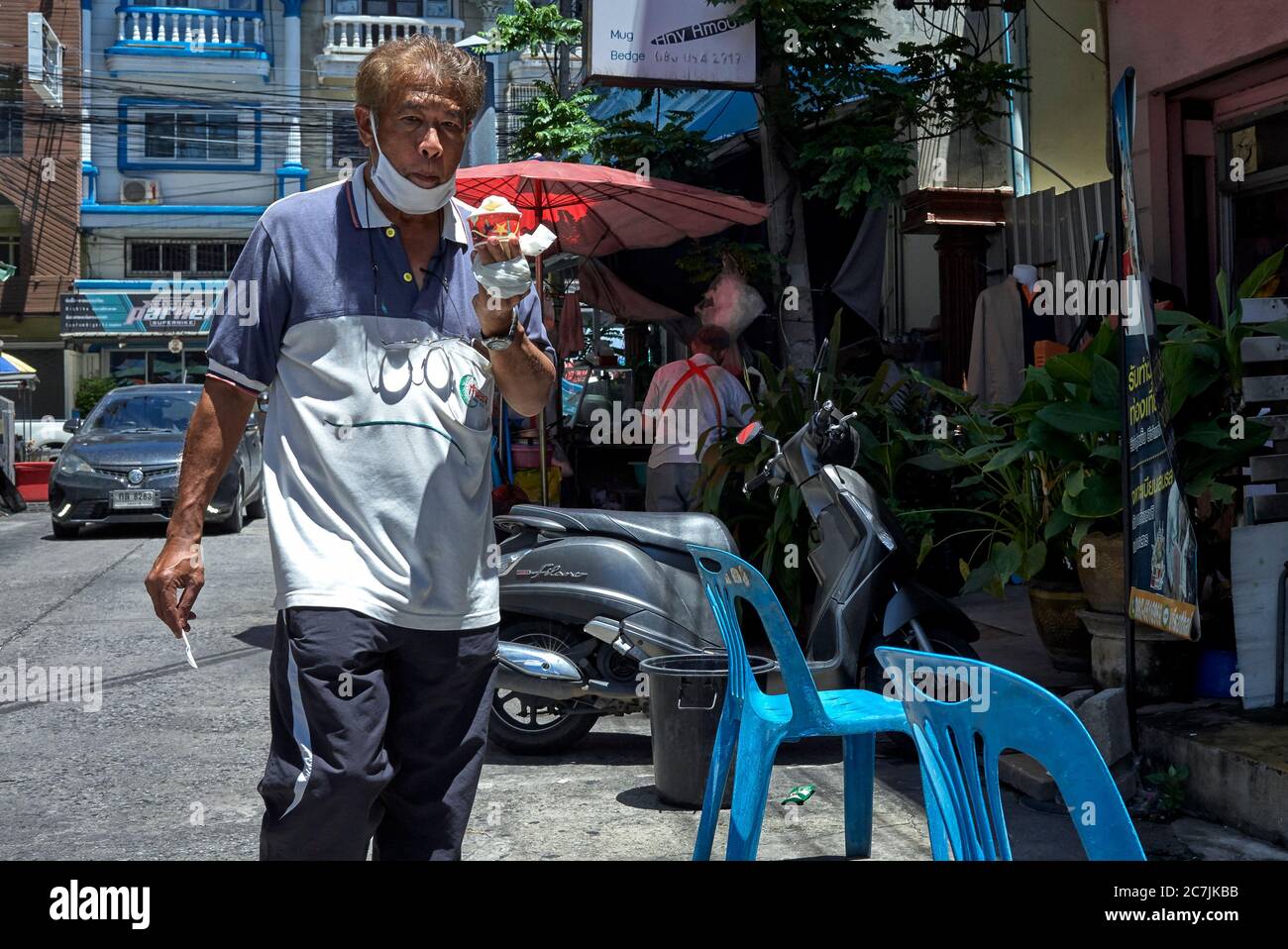 Mann, der Eis isst und die Straße entlang läuft. Thailand Südostasien Stockfoto