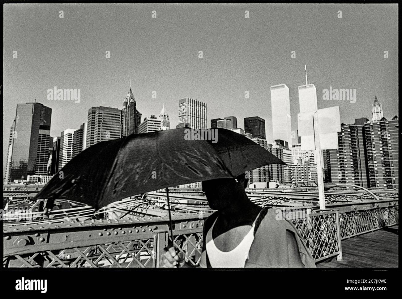 USA, New York, Mann mit Schirm auf der Brooklyn Bridge, World Trade Center im Hintergrund vor den Terroranschlägen vom 11. September 2001 Stockfoto