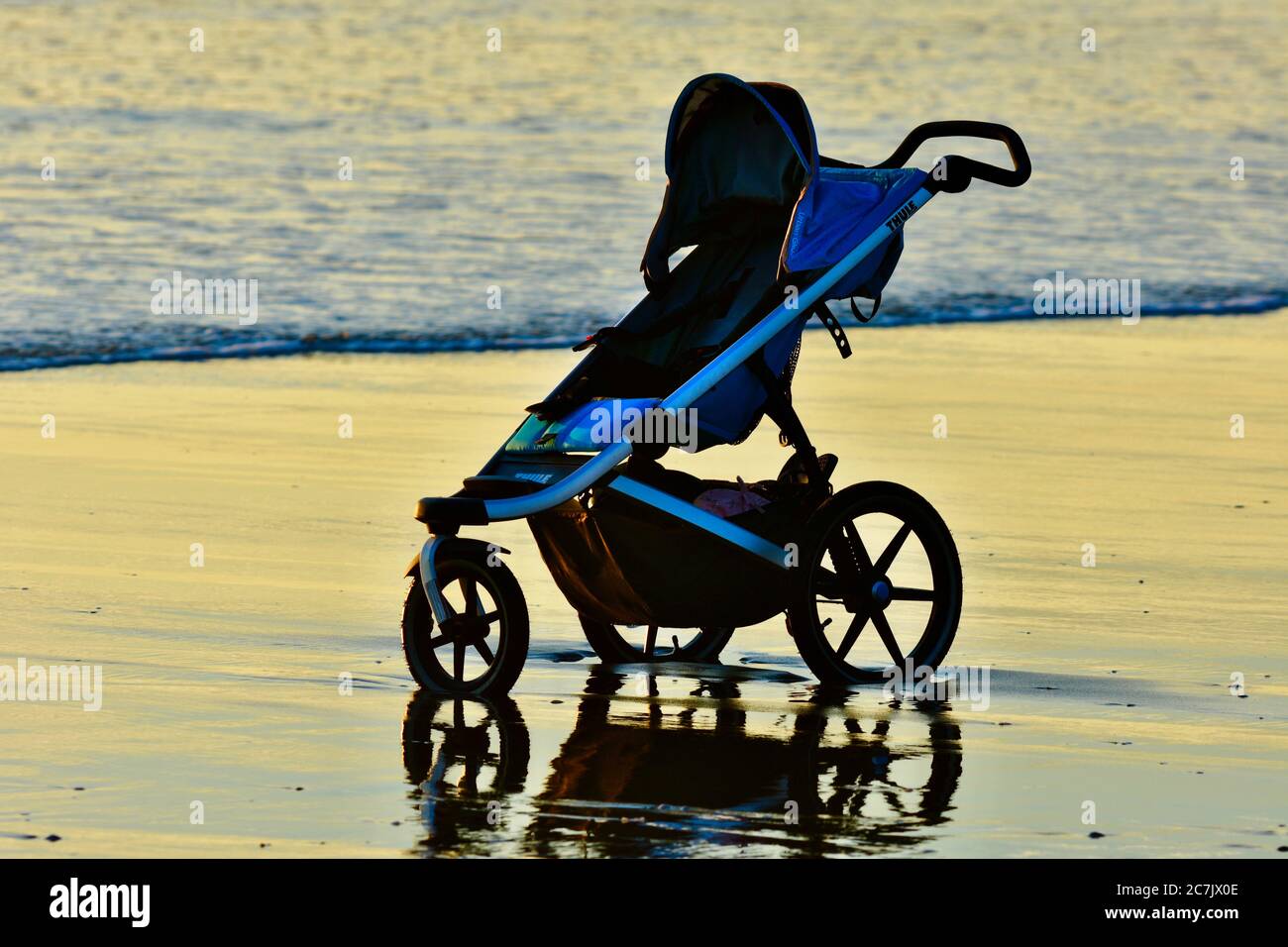 Karioitahi Beach, Auckland, Neuseeland - 2019. Dez.: Ein Kinderwagen am  Strand; Meereswellen berühren die Räder Stockfotografie - Alamy
