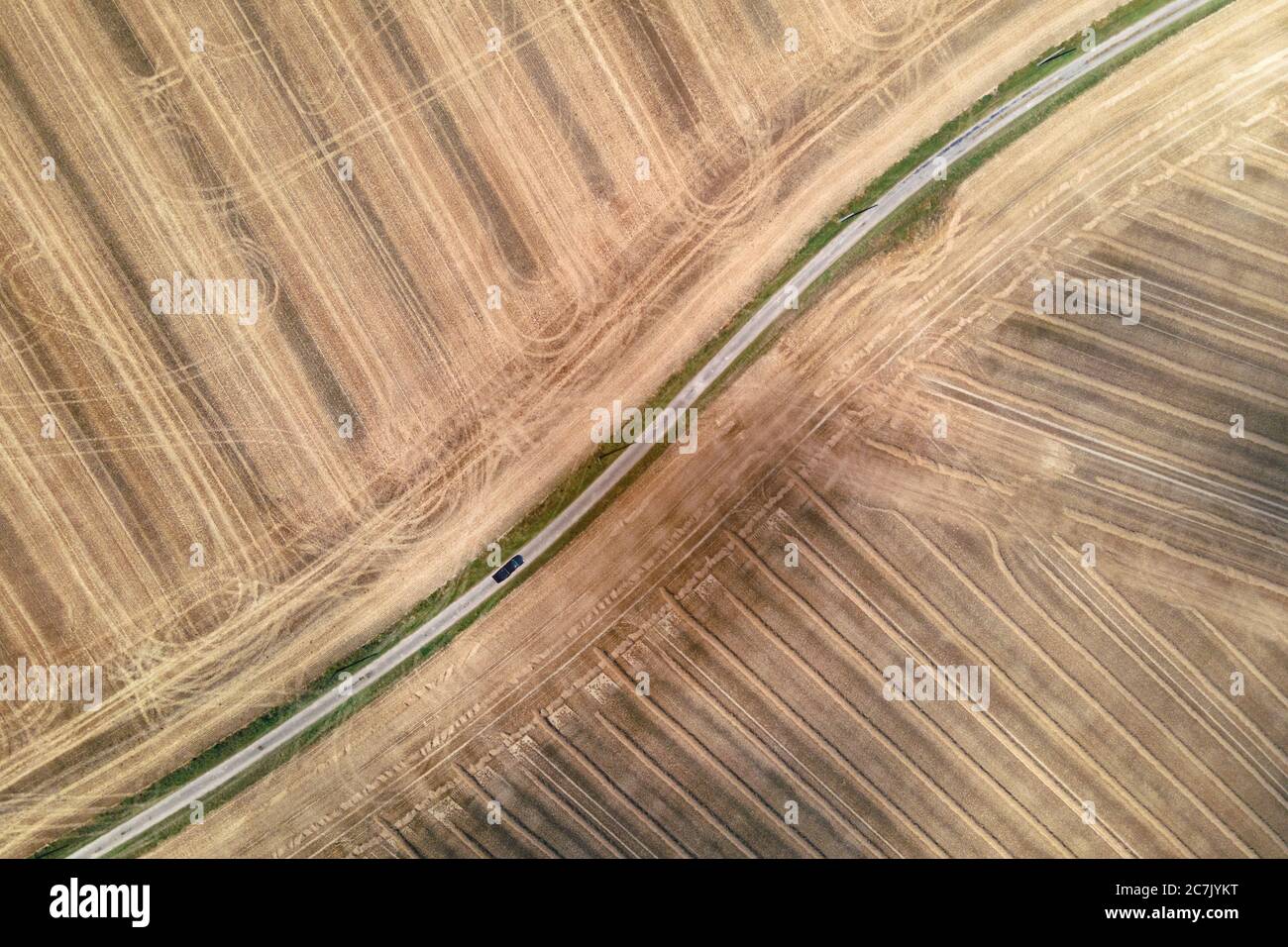 Auto fahren auf einer ländlichen kleinen Straße von geernteten Feldern umgeben, Luftdrohne Blick Stockfoto