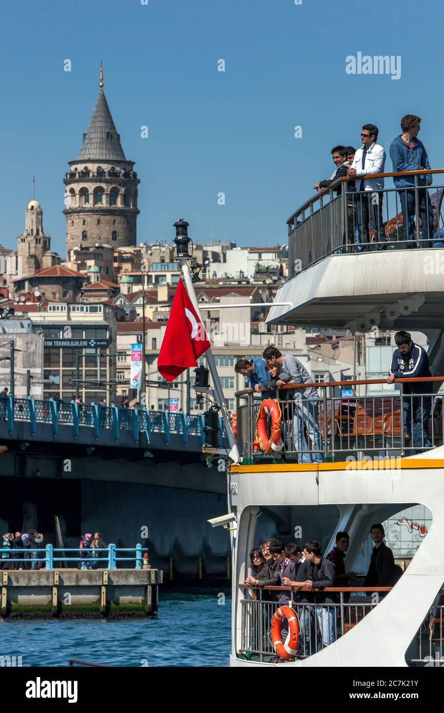 Passagiere an Bord einer Fähre verlassen den Hafen am Goldenen Horn im Stadtteil Eminonu in Istanbul in der Türkei. Im Hintergrund steht der Galata Tower. Stockfoto