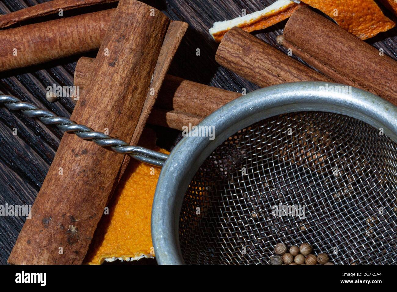 Zimt, Orangenkrusten, Gewürze und Metallsieb auf einem Holztisch Stockfoto