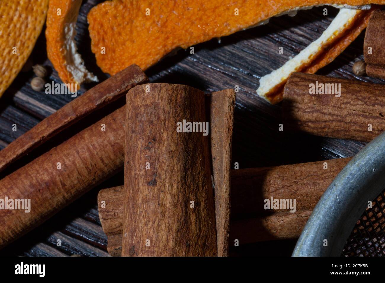 Zimt, Orangenkrusten, Gewürze und Metallsieb auf einem Holztisch Stockfoto