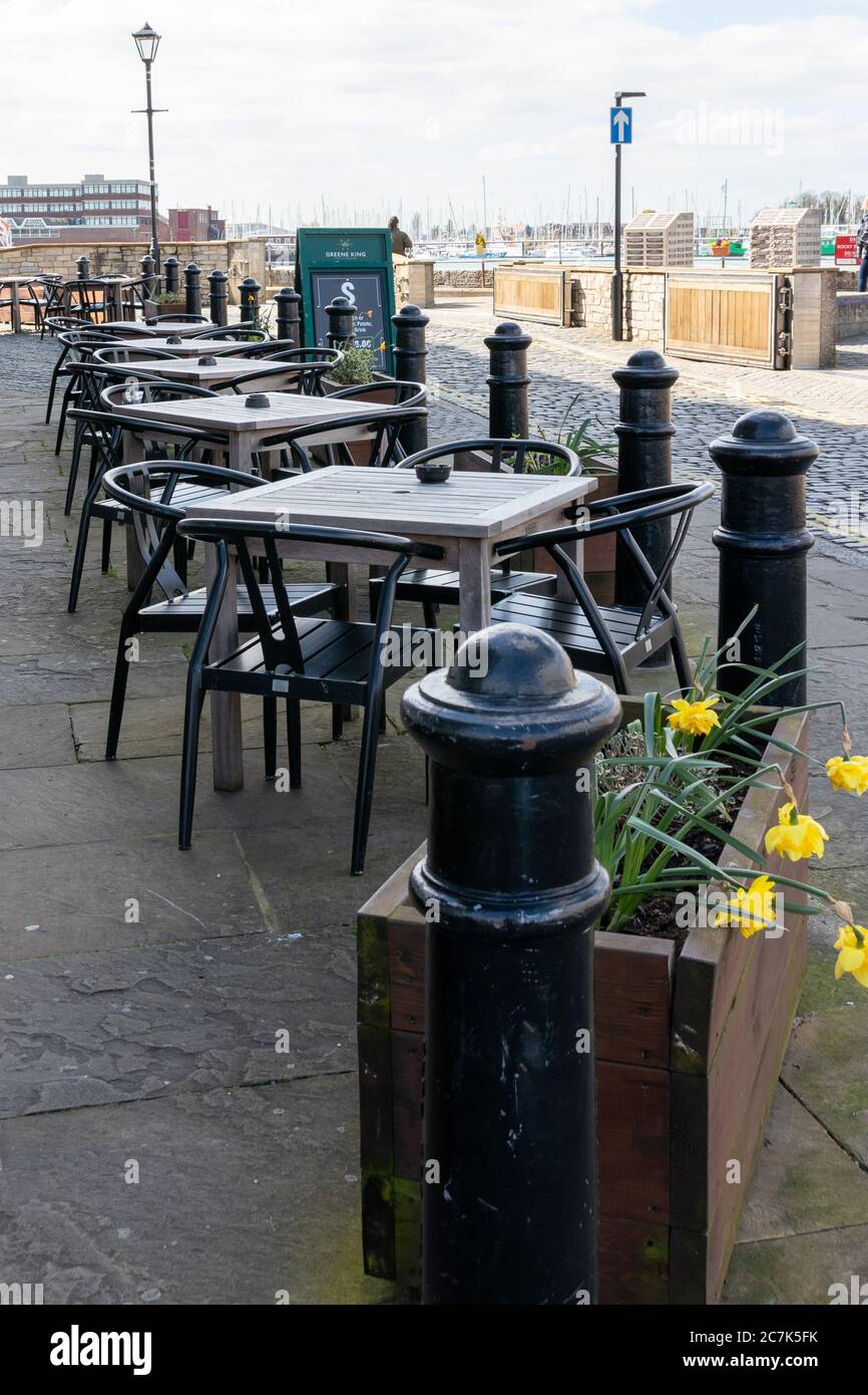 Leere Stühle und Tische vor einem Pub ohne Kunden Stockfoto