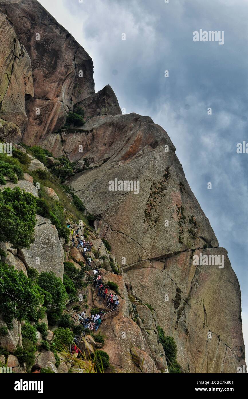 Menschen, die einen vertikalen Hügel mit riesigen starken Felsen und blauen Himmel klettern Stockfoto