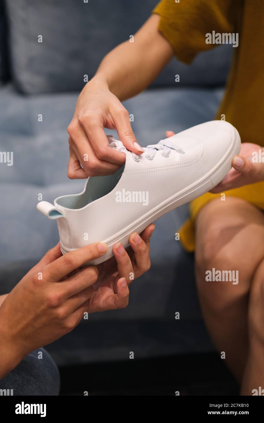 Close up Fashion Consultant geben weißen Sneaker an Kunden im Showroom Stockfoto