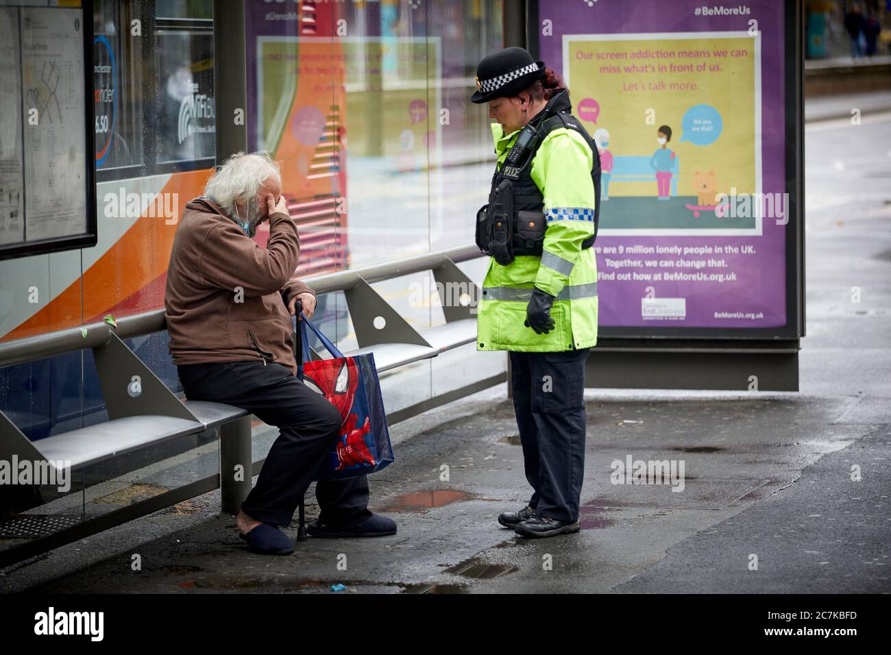 Eine reife Polizistin plaudert mit einem ehrwürdigen OAP-Mann am Manchester Piccadilly Busbahnhof Stockfoto