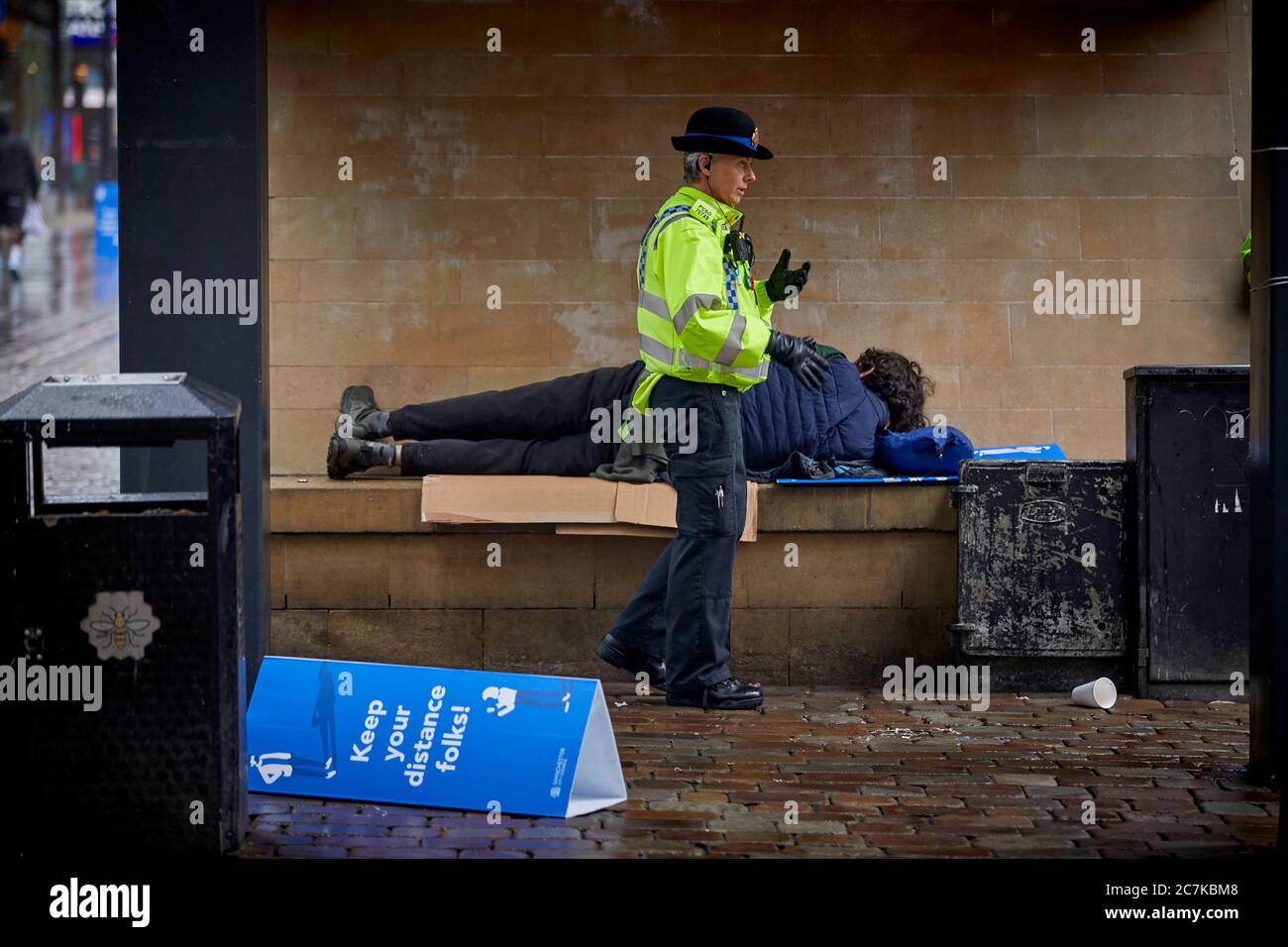 Manchester Market Street ein PCSO-Offizier weckt einen Obdachlosen auf Stockfoto