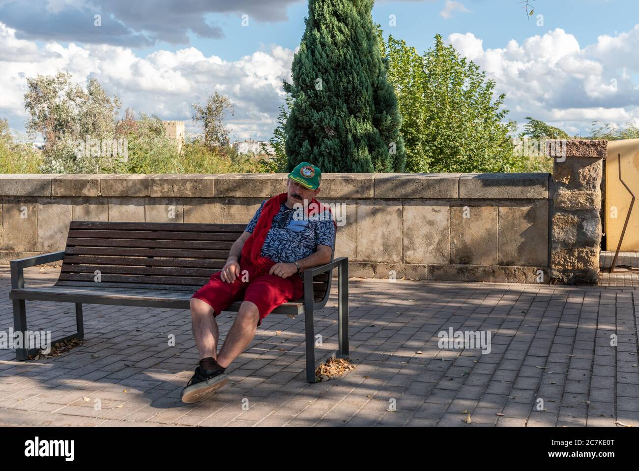 Urlaub ist harte Arbeit! Ein Tourist hat eine schnelle Siesta auf einer schattigen Bank beim Alcázar de los Reyes Cristianos in Córdoba Stockfoto
