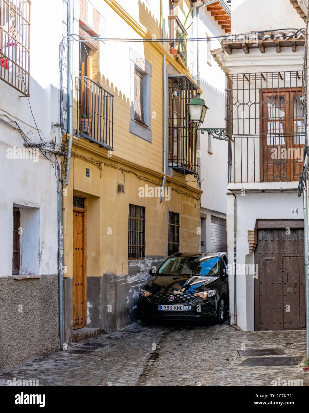 Enger Druck. In der Calle de San Juan de los Reyes in Granadas historischem maurischen Viertel Albaicin quetscht sich kaum ein kleines Auto zwischen den Gebäuden. Stockfoto