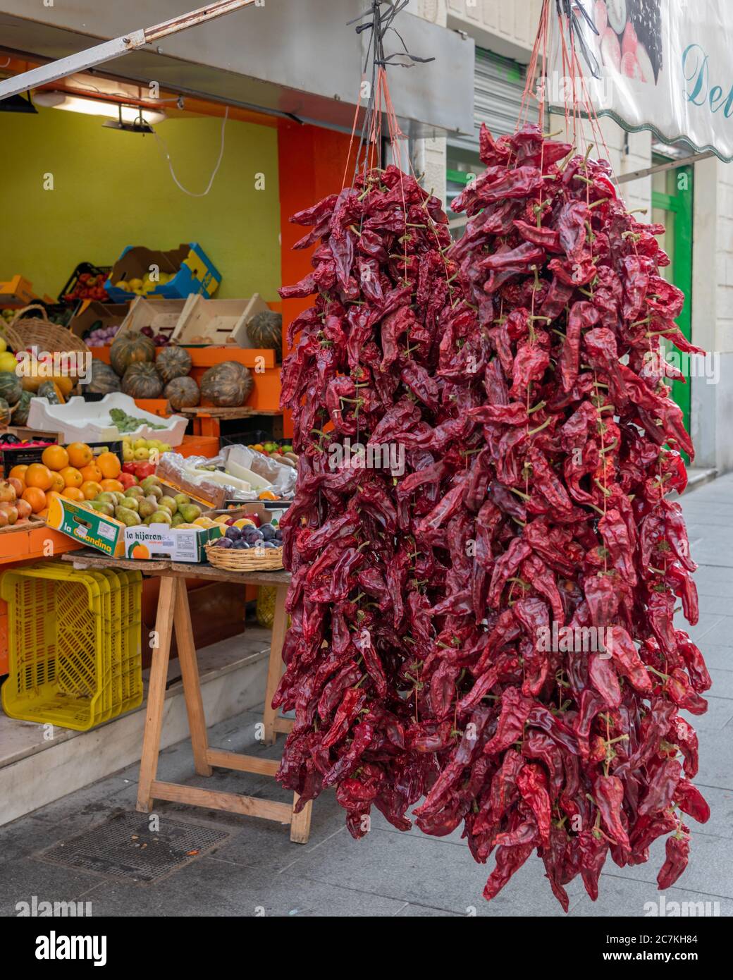 Vor dem Obst- und Gemüseladen Fruteria Delicias De La Huerta in der Calle Puentezuelas, Granada, hängen getrocknete rote Chilischoten Stockfoto