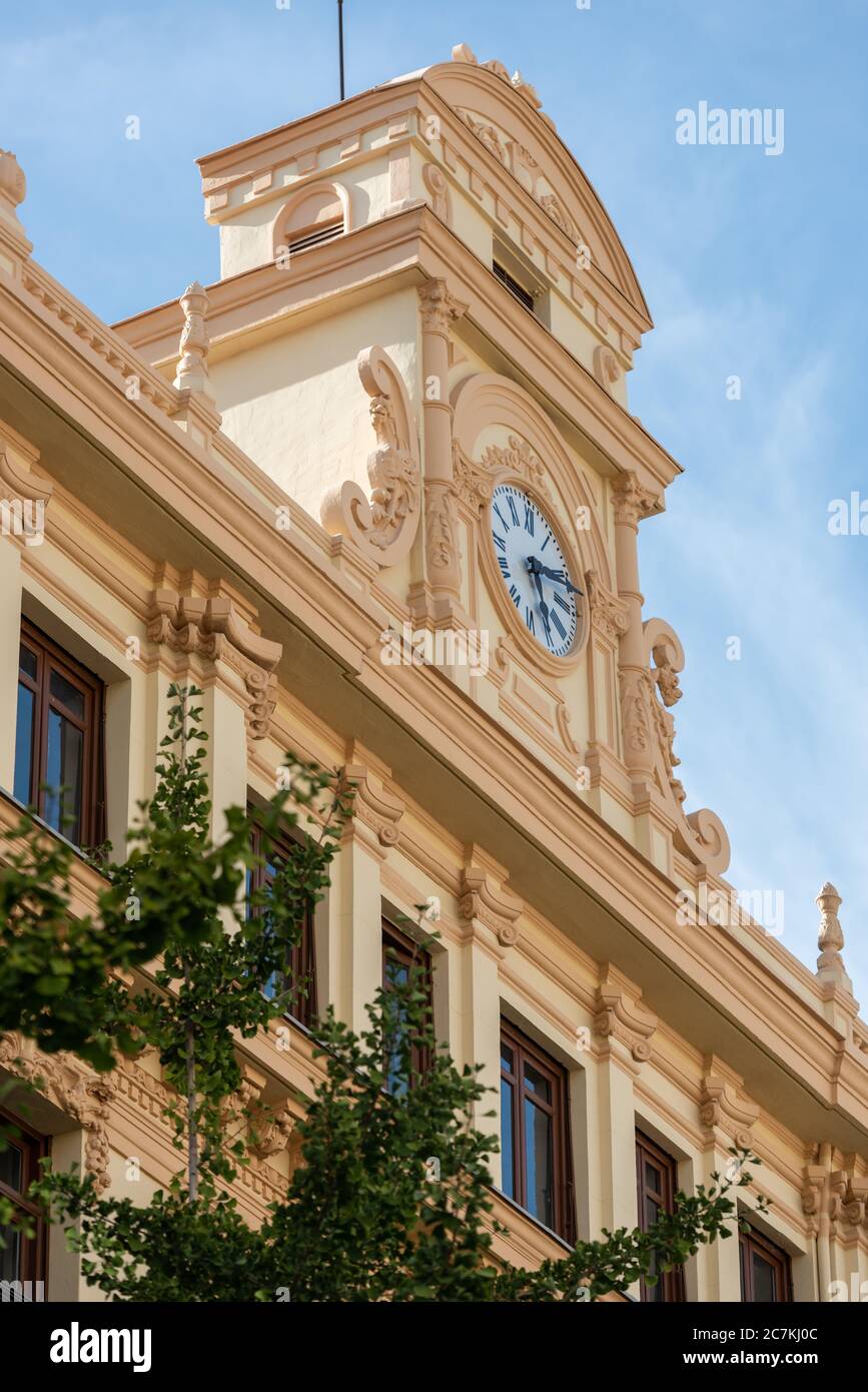 Ein aufwändiger Uhrenturm auf einem der vielen prachtvollen Gebäude, die die Calle Gran Via de Colon in Granada säumen Stockfoto
