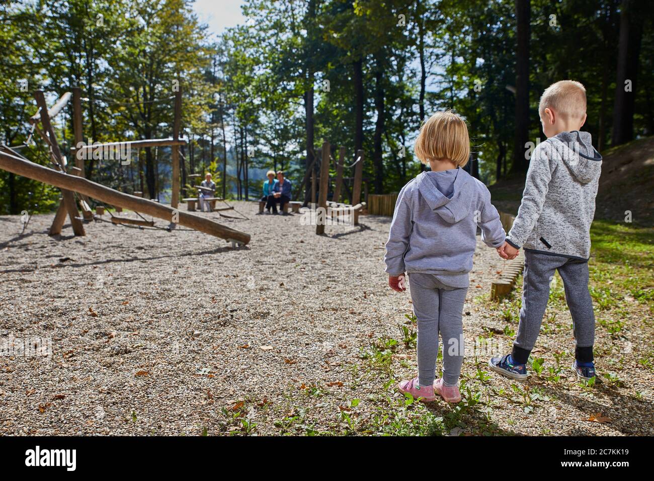 Kleiner Junge und ein Mädchen halten die Hände von jedem Andere während des Stehens auf dem Spielplatz Stockfoto