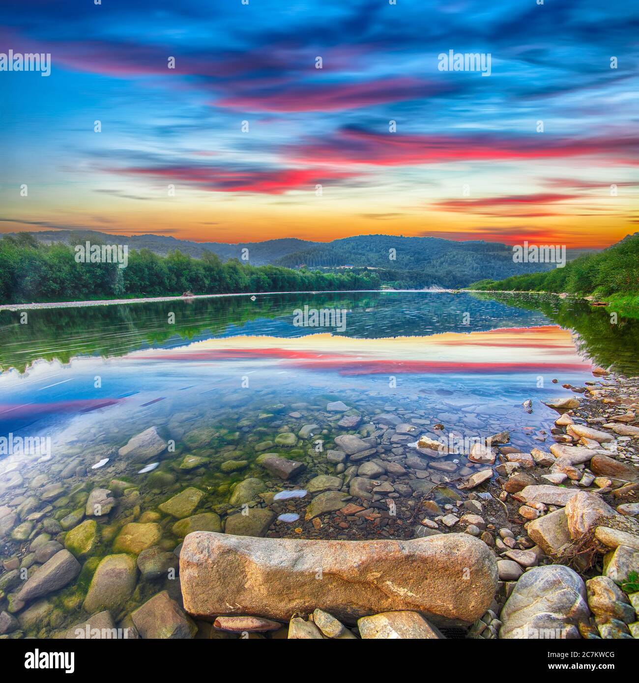 Gebirgsfluss von Wasser in den Felsen mit majestätischem Sonnenuntergang Himmel. Klarer Fluss mit Felsen. Steinvordergrund. Lange Belichtung Stockfoto