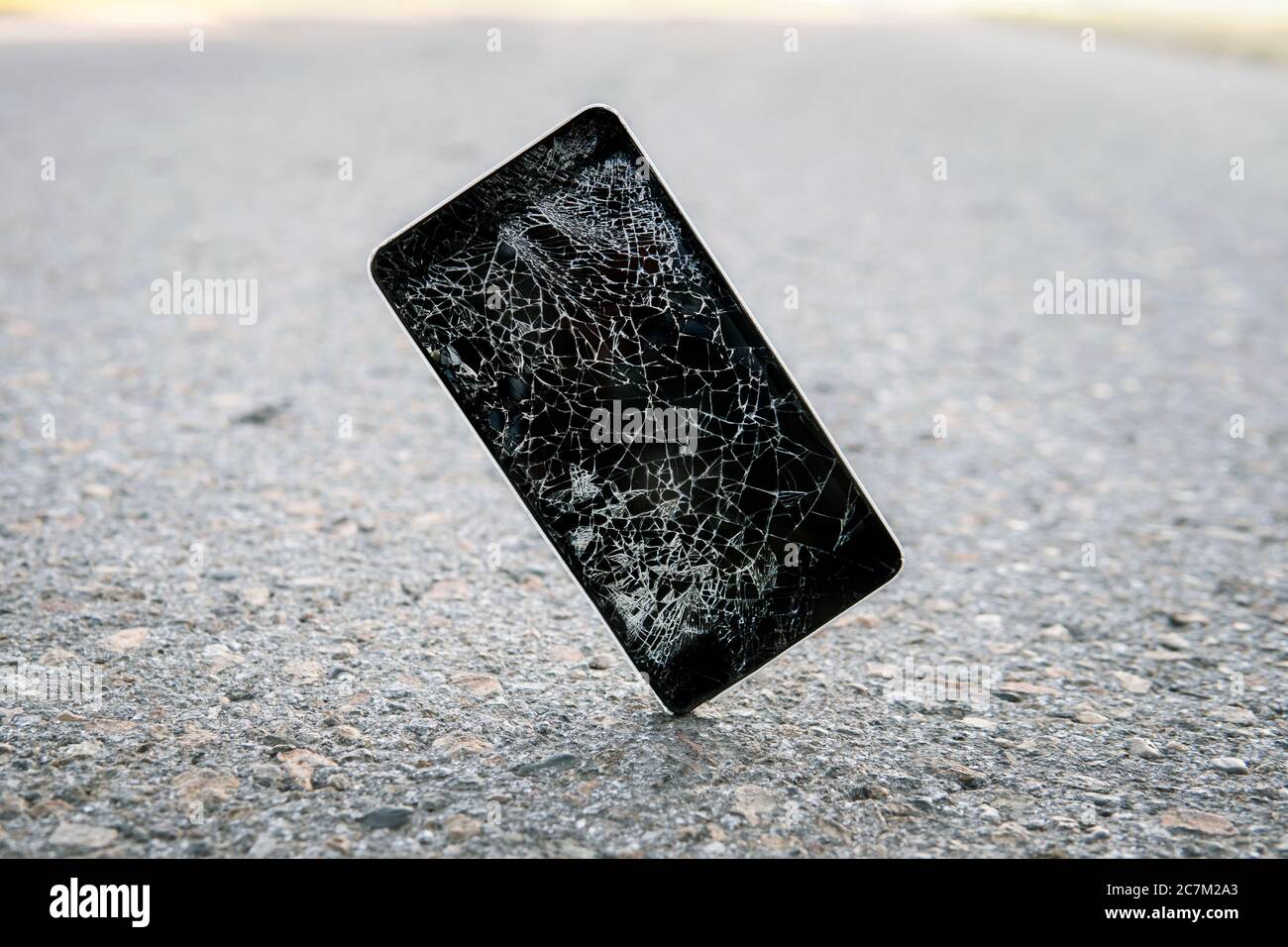 Telefon, während auf der Straße fallen. Handy-Risse bei der Aufprall auf Beton. Modernes Smartphone mit stark gebrochenem Bildschirm fiel auf den Asphalt. Stockfoto