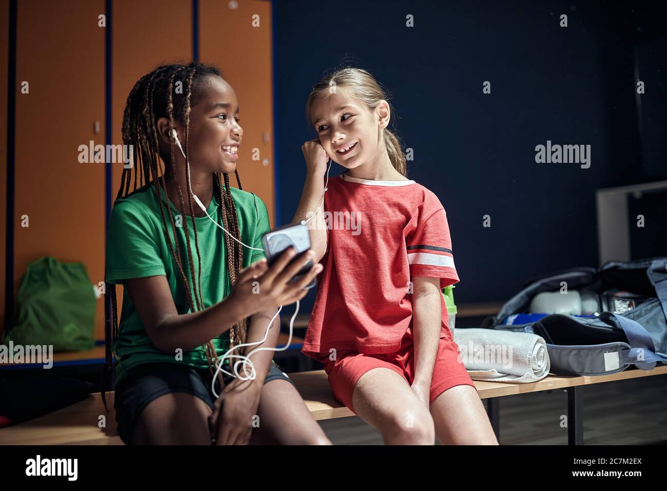 Lächelnd Sport Kinder Mädchen vor dem Training Musik am Telefon in der Umkleidekabine hören. Stockfoto