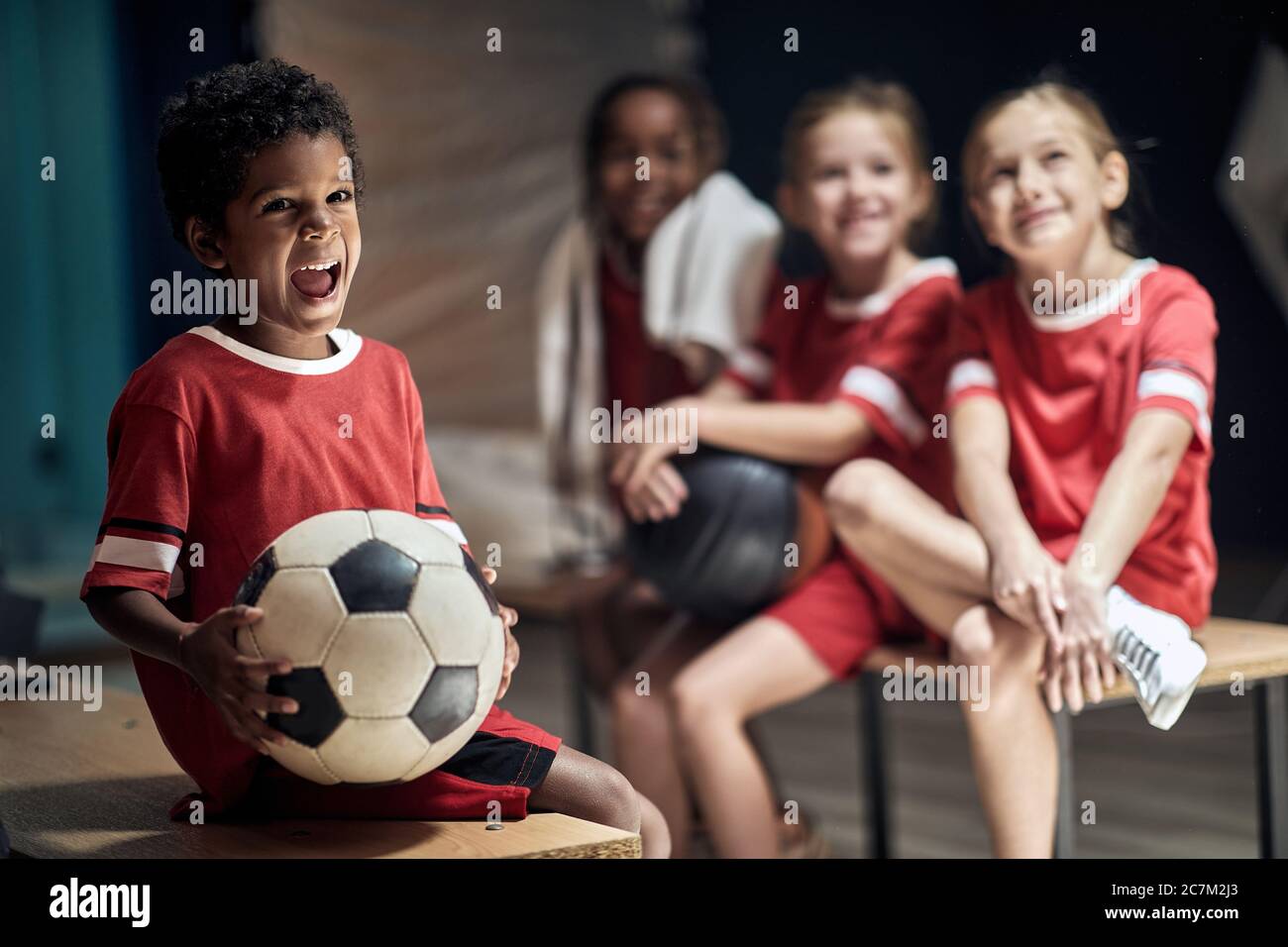 Lächelnder Junge mit Fußball in Umkleideraum.Fußballspieler Vorbereitung für das Spiel in Umkleideraum. Stockfoto