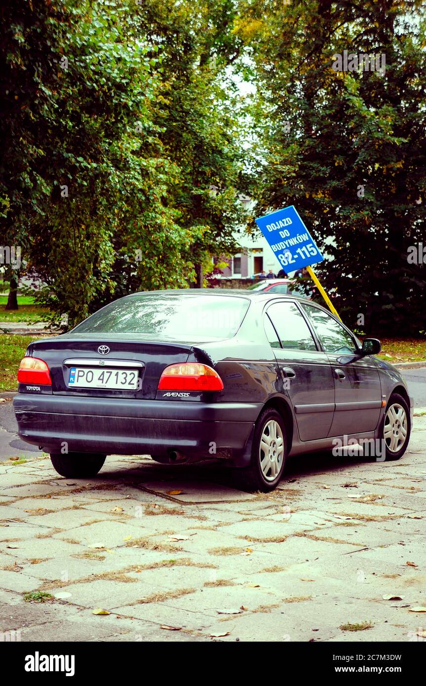 Ich habe Toyota Avensis vor einem beschädigten Schild geparkt, an einem Bürgersteig in der Stadt. Stockfoto