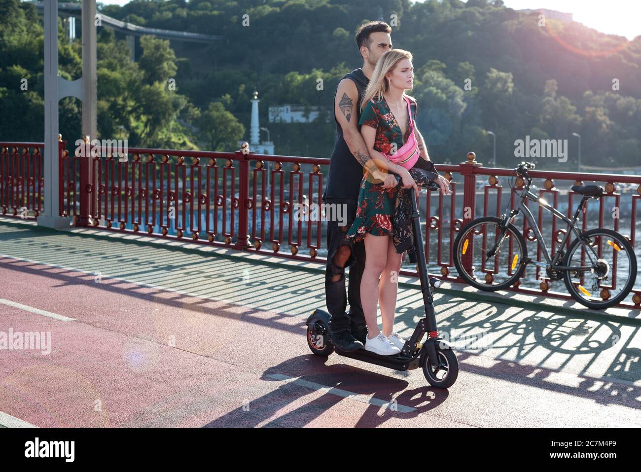 Kiew, Ukraine - 11. Juli 2020. Fußgängerbrücke. Junge attraktive Paar in der Liebe Reiten ein elektrisches einrad zusammen genießen Sommertag Stockfoto
