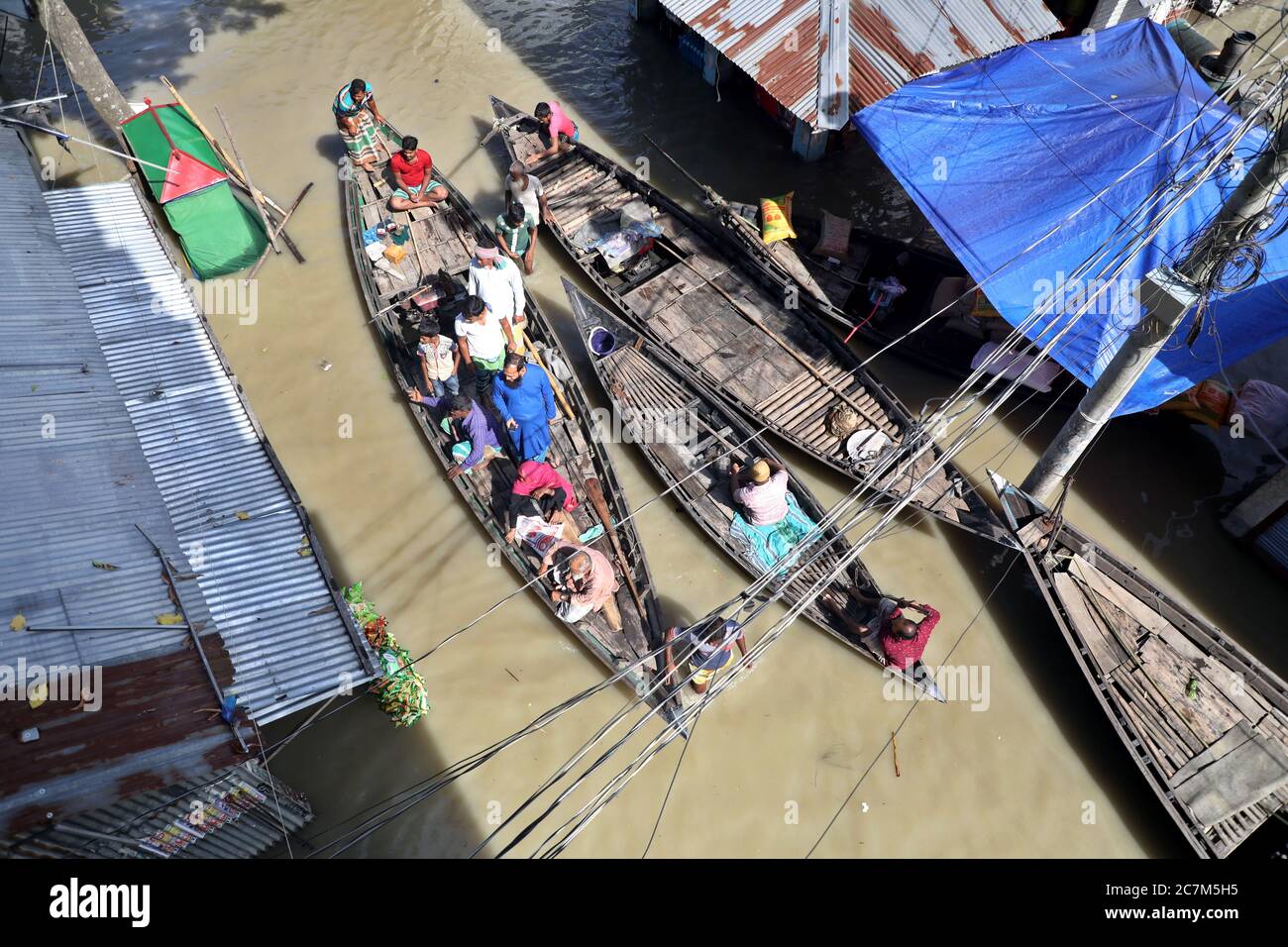 Dhaka, Bangladesch - 17. Juli 2020: Boote watet durch kasttiefes Wasser, um in ein sichereres Unterschlupf zu ziehen, als die Flut Mekhula Bazar von Dohar in Dhaka trifft, Stockfoto
