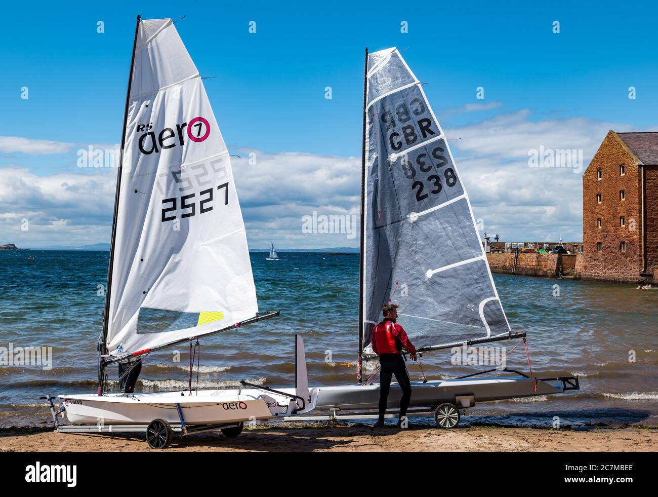 North Berwick, East Lothian, Schottland, Großbritannien, 18. Juli 2020. UK Wetter: Sommersonne in der Küstenstadt.das erste Rennen des East Lothian Yacht Club, das heute nach Lockdown Lockdown genannt "Lockdown Shakedown" stattfinden soll, wurde wegen der steifen Brise, die den Rettungsdienst gefährdet hätte, abgesagt. Einzelpersonen gingen in ihren Segeljollen vom West Bay Strand trotz des Windes aus Stockfoto