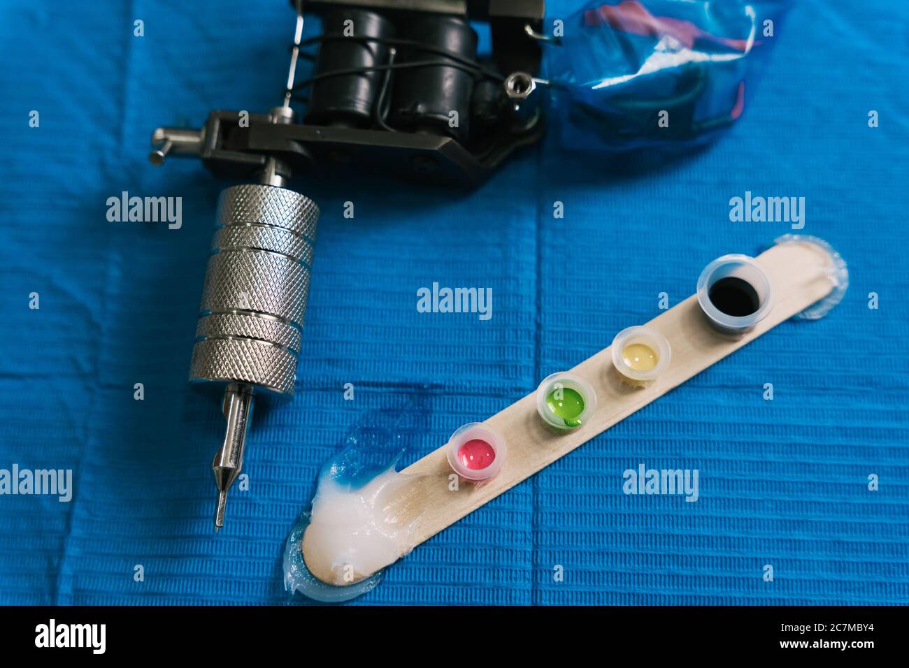 Draufsicht von Tätowiermaschine und Tintenbehälter auf Eine blaue Oberfläche Stockfoto