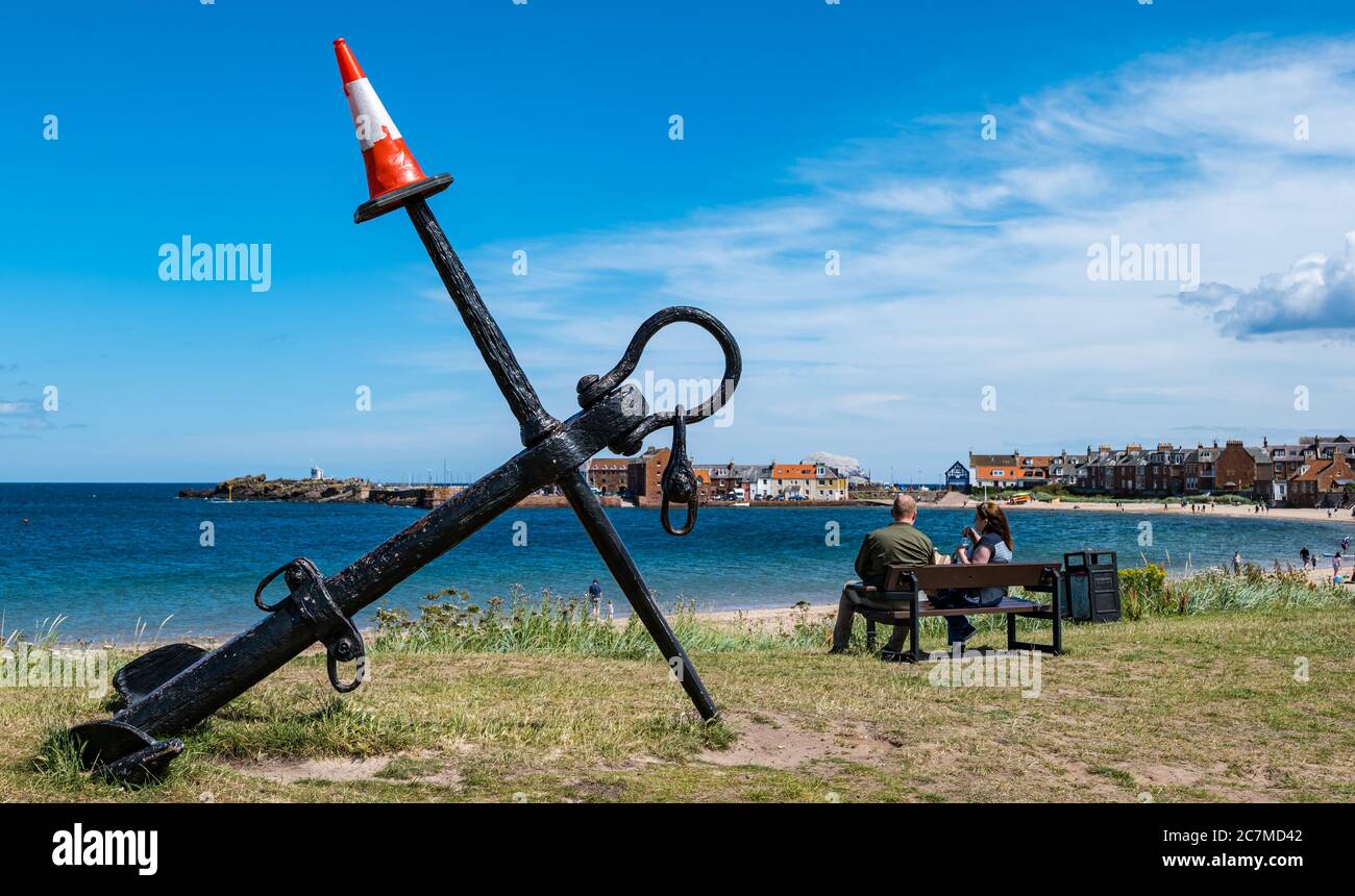 North Berwick, East Lothian, Schottland, Großbritannien, 18. Juli 2020. UK Wetter: Sommersonne in einer sehr geschäftigen Küstenstadt, die wieder normal ist, wenn auch mit sozialen Distanzierungsmaßnahmen in Kraft. Der ikonische Anker am West Beach hat einen Verkehrskegel erworben Stockfoto